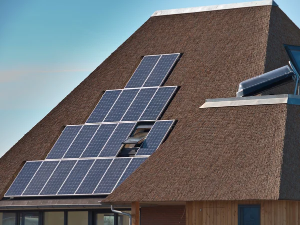 Painéis solares em um telhado de palha — Fotografia de Stock