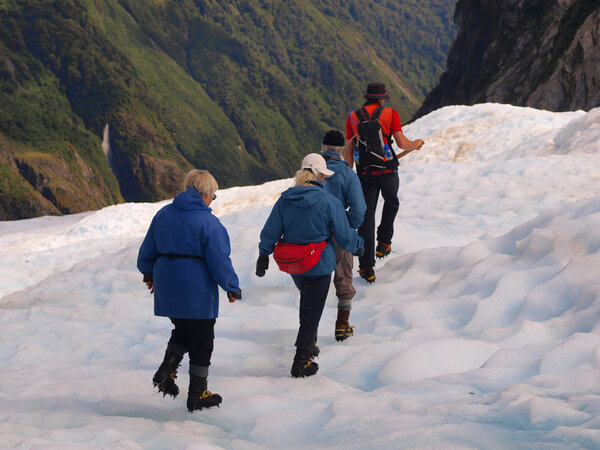Group of tourists following a guide on a glacier