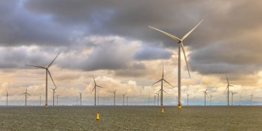 Denizdeki Windfarm açıklarında. IJsselmeer 'in sularında bulutlu gökyüzünün altında bir grup rüzgar türbini. Rüzgar enerjisi sürdürülebilirliğe giden yeşil tepside elektriğin en ucuz formlarından biri haline geldi. Hollanda.