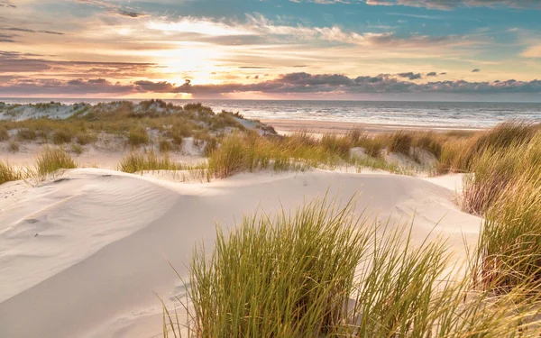Hollanda, Ameland adasından, Kuzey Denizi 'nde gün batımının üzerindeki kum tepesinden manzara