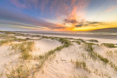 Sahil ve kum tepeleri Hollanda 'nın Wijk aan Zee' den Kuzey Denizi üzerinde gün batımında görülen kıyı manzarası