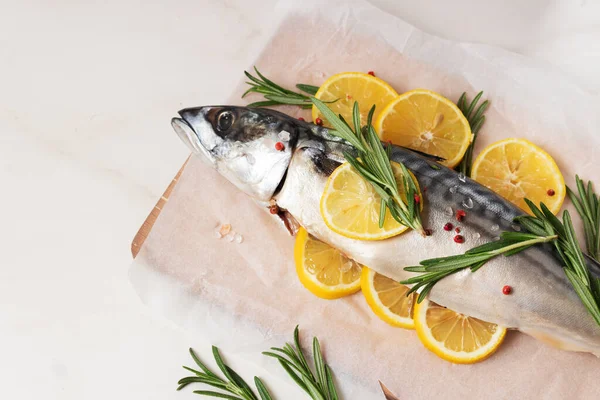 Färsk fisk med citron, rosmarin, salt och rosépeppar på träskiva och pergament. — Stockfoto