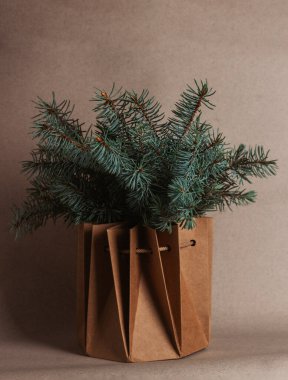 Bej-gri arka planda, el sanatları kutusundaki ladin dallarının Noel kompozisyonu. Dikey yönelim.