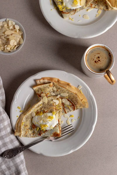 Крепления, тонкие блинчики с маком, лимон и сметана на коричневом фоне. Здоровый завтрак в солнечное утро . — стоковое фото