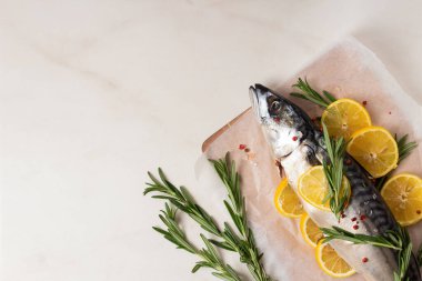 Tahta üzerinde limonlu, biberiyeli, tuzlu ve pembe biberli taze balık ve parşömen.. 