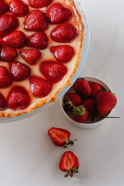 Mermer arka planda çilekle süslenmiş lezzetli çilekli tart. Üst görünüm 