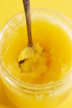 Sarı arka planda açık cam bir kavanozda rafine edilmiş kahve. Yakın çekim.