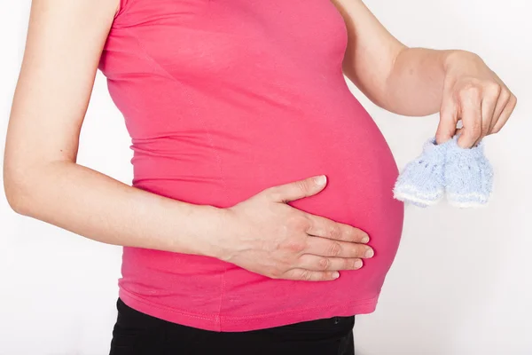 Pregnant woman holding baby slippers — Stock Photo, Image