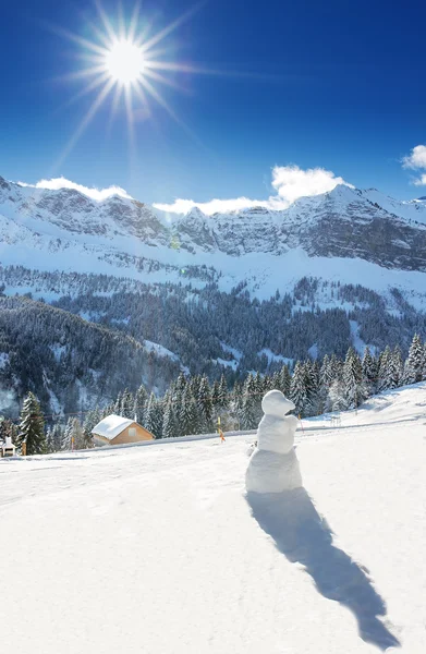 Bosque blanco, cielo azul, sol y muñeco de nieve en los Alpes suizos durante un hermoso día soleado, estación de esquí Klewenalp, Suiza Central — Foto de Stock