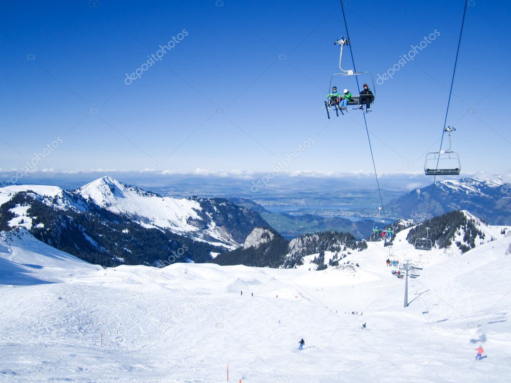 Skiers skiing in Klewenalp ski resort with view to Lucerne lake, Central Switzerland