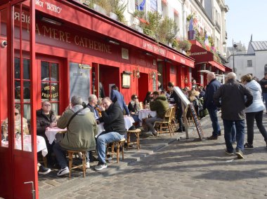 Paris, Fransa - 5 Mart 2022: Fransa 'nın Paris kentindeki Montmartre semtindeki kırmızı restoranın açık terasındaki insanlar.