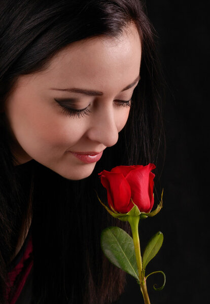 Attractive young woman smells a rose