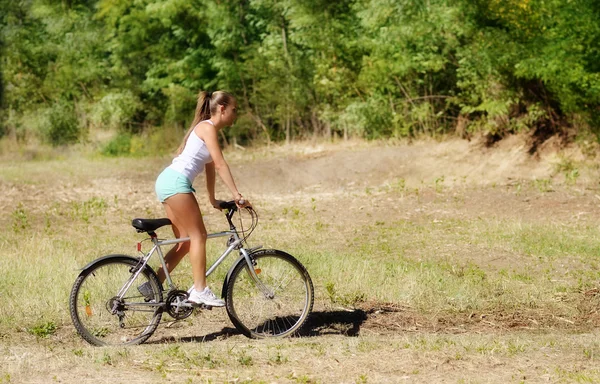 Красивая женщина с велосипедом в парке — стоковое фото