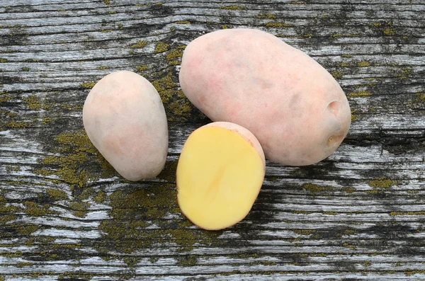 Potatoes on a rough wooden background — Stock Photo, Image