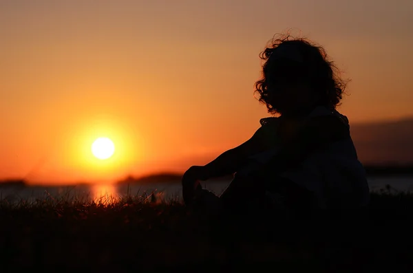 Расслабляющий маленький ребенок на закате — стоковое фото