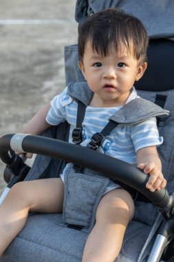 Mutlu ve şirin Asyalı bir çocuğun portresi. Bebek arabasının üzerinde akşam vakti oturuyor.