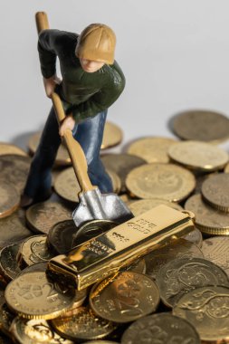 Endüstriyel Mühendislik işçisi altın külçesi ve madeni parayla iş ve endüstri konsepti kazıyor. Altın, gümüş, bronz madeni para ile para kazanmak için çok çalışmak gibi.