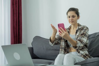 Bilgisayarın başındaki kız telefonu elinde tutuyor. Modern çalışma. Z Nesli.