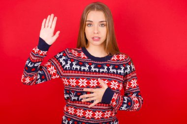 Kafkasyalı genç bir kız Noel süveteri giyiyor. Göğsünde ve avuç içinde yemin ediyor. Sadakat yemini ediyor.