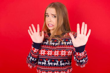 Kafkasyalı genç bir kız yılbaşı süveteri giyiyor. Korkudan dehşete düşmüş ve korkmuş. El kol hareketi yapmayı kes, şok içinde bağır. Panik konsepti.