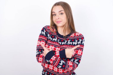 Beyaz arka planda Noel süveteri giyen beyaz saçlı genç beyaz kız kollarını kavuşturuyor ve farklı taraflardaki iki nesne ya da varyant arasında tereddüt ediyor. Karar vermede yardıma ihtiyacı var