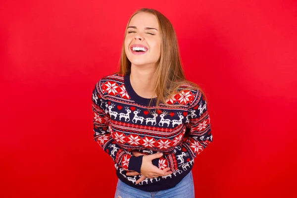 年轻的高加索女孩穿着圣诞毛衣 笑得很开心 笑得很大声 因为有一个可笑的疯狂笑话 她的手还在身上 — 图库照片