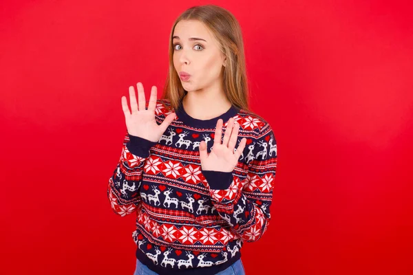 身穿圣诞毛衣的年轻高加索女孩手心移开 带着恐惧和厌恶的表情表示拒绝和否认 停止和禁止 — 图库照片