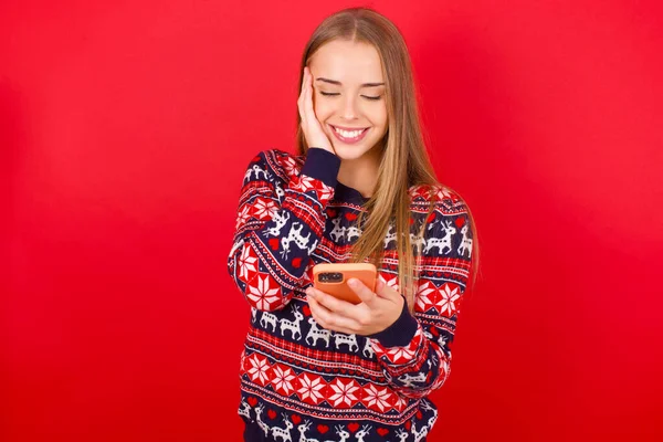 Menina Caucasiana Jovem Vestindo Camisolas Natal Fundo Vermelho Segurando Nas — Fotografia de Stock