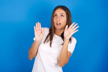 Güzel, genç bir kadın avuçlarını ileri uzatıyor ve tavandan korkuyla bakıyor. Kendini görünmez tehlikeden korumaya çalışıyor..