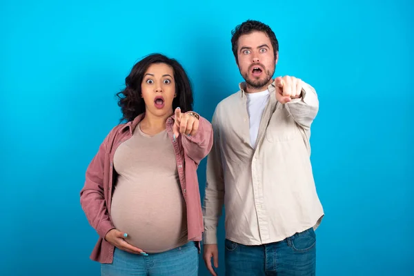 Young Couple Expecting Baby Standing Blue Background Pointing Finger Surprised — Stock Photo, Image