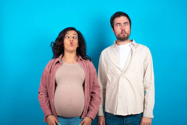 Jovem Casal Esperando Bebê Contra Fundo Azul Fazendo Cara Peixe — Fotografia de Stock