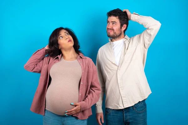 Junges Paar Das Ein Baby Vor Blauem Hintergrund Erwartet Verwirrt — Stockfoto