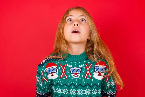 Surprised Brunette Kid Girl Knitted Sweater Christmas Red Background Shrugs — Stock Photo, Image