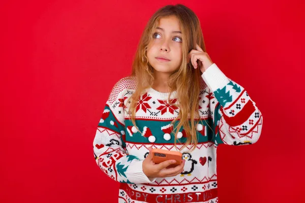 Ragazza Bruna Bambino Maglia Maglione Natale Sfondo Rosso Tenendo Gadget — Foto Stock