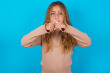 Mavi arka planda süveter giyen esmer kız reddedilmiş kızgın bir ifade var..