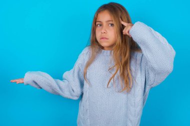 Mavi arka planda mavi örülü süveter giyen esmer kız avuç içinin açık olması, fotokopi alanını göstermesi ve alnını işaret etmesinden rahatsız olmuş. Bunu bir düşün..
