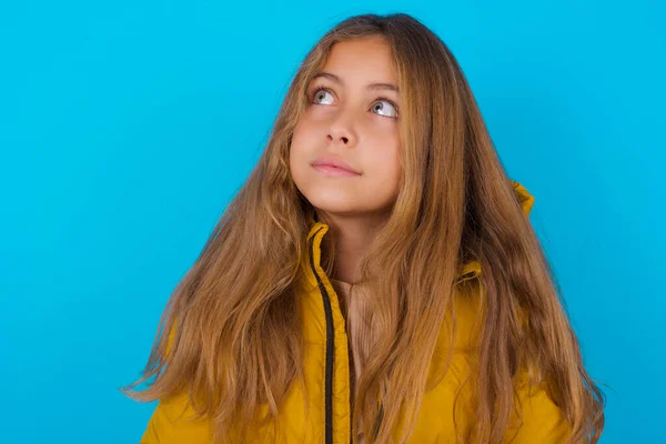 Brunette Kid Girl Wearing Yellow Jacket Blue Background Looking Aside — Stock Photo, Image