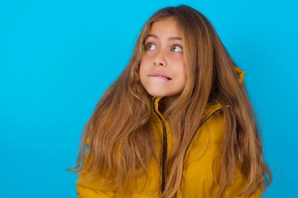 Niesamowite Brunetka Dziecko Dziewczyna Noszenie Żółty Kurtka Niebieskim Tle Gryzienie — Zdjęcie stockowe