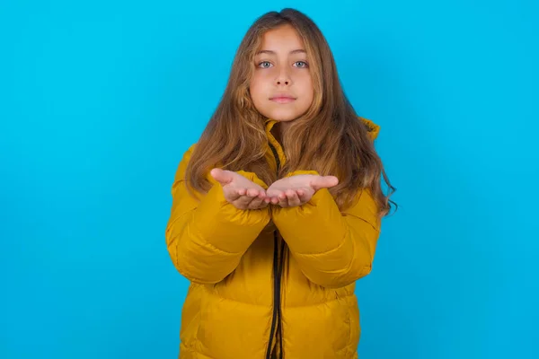 Brunetka Dziecko Dziewczyna Noszenie Żółty Kurtka Niebieskim Tle Trzyma Coś — Zdjęcie stockowe