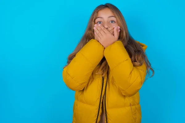 Menina Morena Criança Vestindo Casaco Amarelo Sobre Fundo Azul Chocado — Fotografia de Stock
