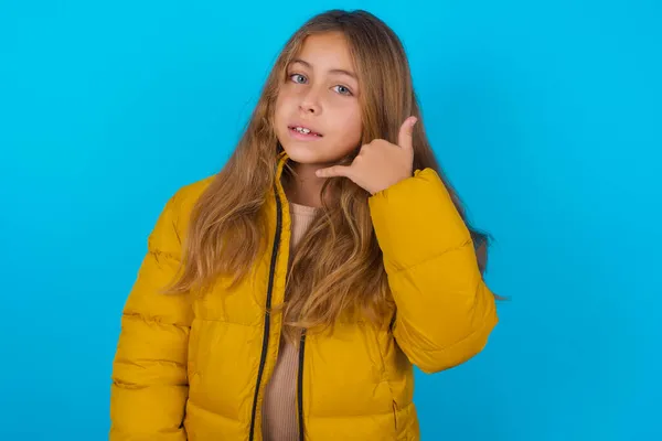Brünettes Mädchen Gelber Jacke Über Blauem Hintergrund Lächelt Und Macht — Stockfoto