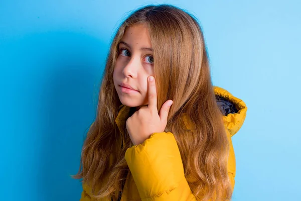Brunetka Dziecko Dziewczyna Żółtej Kurtce Niebieskim Tle Wskazując Oko Patrząc — Zdjęcie stockowe