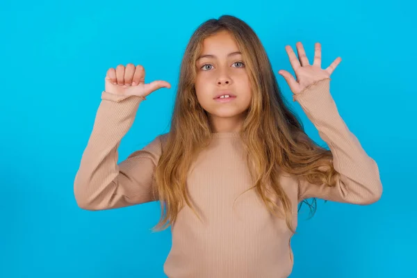 Brunetka Dziecko Dziewczyna Noszenie Sweter Niebieskie Tło Pokazując Wskazując Palce — Zdjęcie stockowe