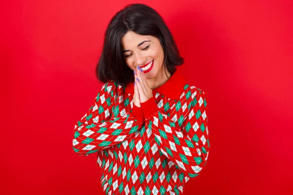 喜びましたブルネットCaucasian女の子身に着けていますニットセータークリスマス以上赤背景笑楽しいですそして維持ヤシ一緒にプレス何か面白い聞く — ストック写真