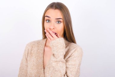 Şok olmuş genç bir kadın elleriyle poz veriyor.