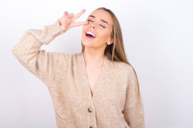 Yüzünde parmakları olan genç bir kadın barış işareti yapıyor. 