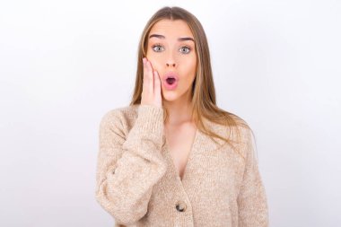 Şok olmuş genç bir kadın el üstünde poz veriyor.