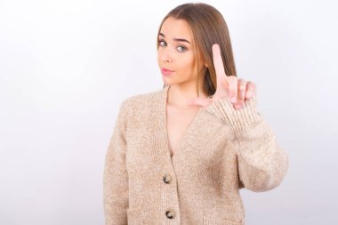 Beyaz arka planda ezik jestleri yapan genç bir kadın.