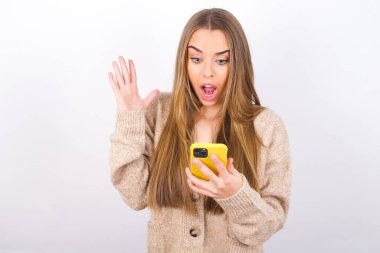 Stüdyoda akıllı telefonuyla poz veren genç bir kadın, ekrana bakarken şok oldu.