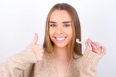 young woman holding retainer and smiling clipart